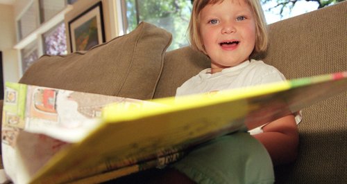 Child Reading a book on a bed