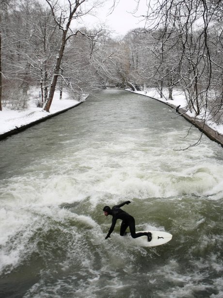Surfer rides a wave on a river in Munich