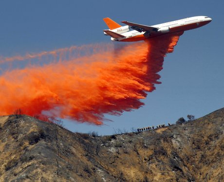 A plane drops fire retardant on a wildfire