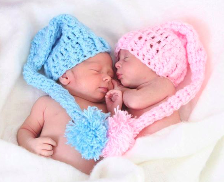 Twin babies with heart shape in their hats