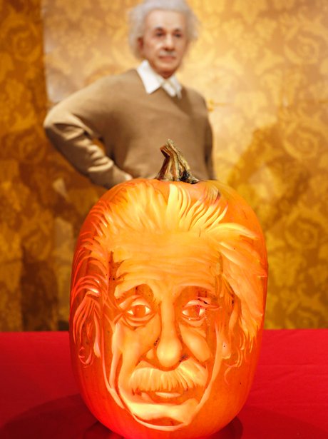 A wax figure of Albert Einstein with a pumpkin carving of his face