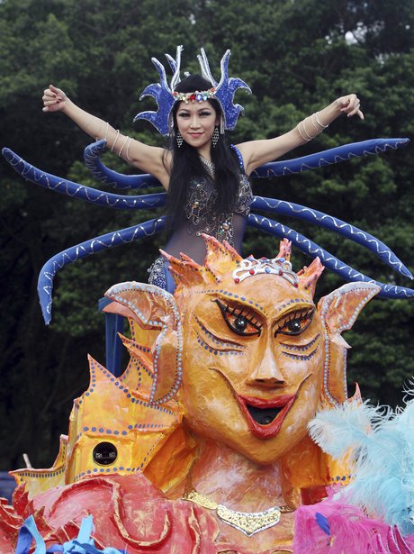 A woman in costume sits atop a float