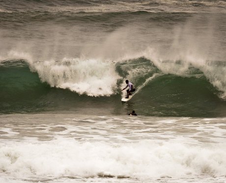 surfer rides a wave in cornwall