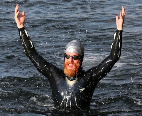 Sean Conway raises his arms in triumph whilst in the sea