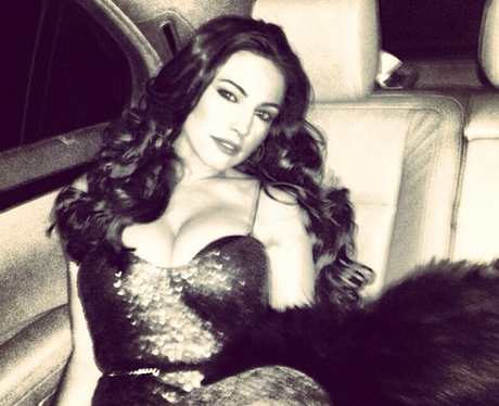 Kelly Brook poses seductively on back seat of car and shows off her cleavage