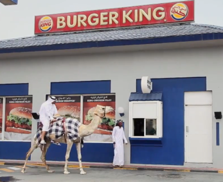 A man riding a camel outside Burger King