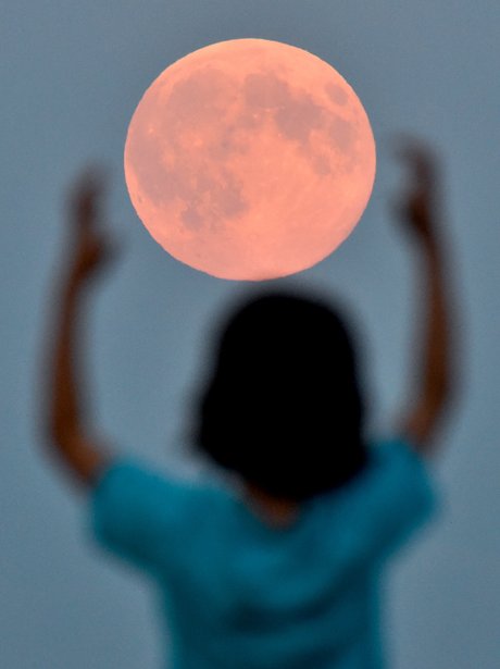 A boy pretending to hold the Supermoon