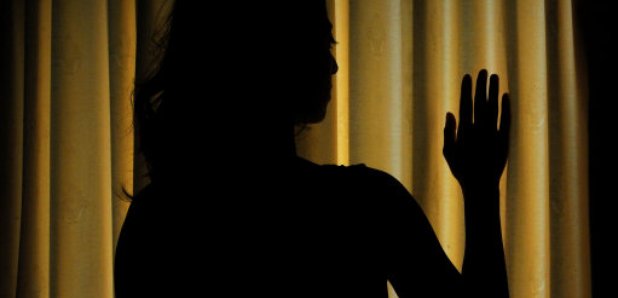 Silhouette of female model by curtains 